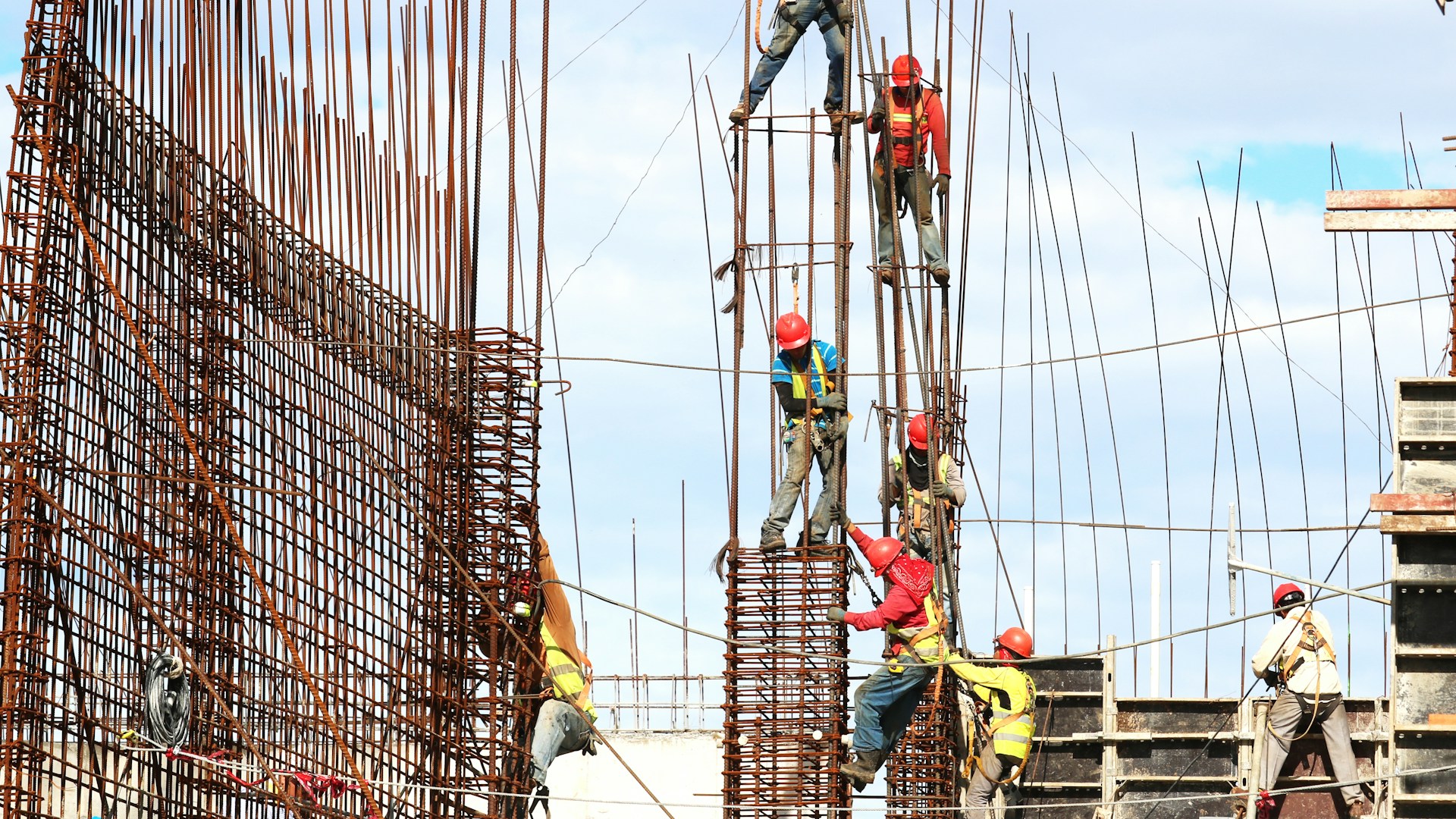 Operários montando armação de aço na base de um prédio em construção
